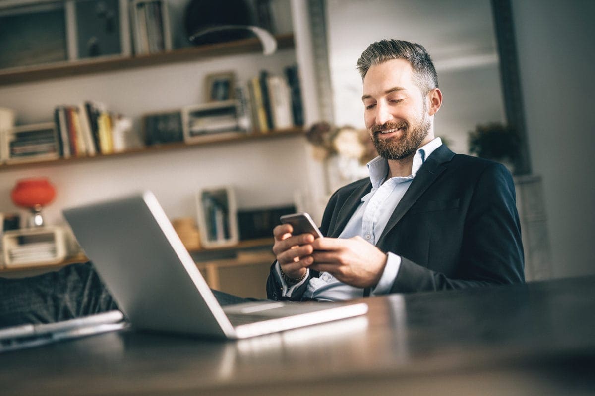 A happy businessman checks his phone