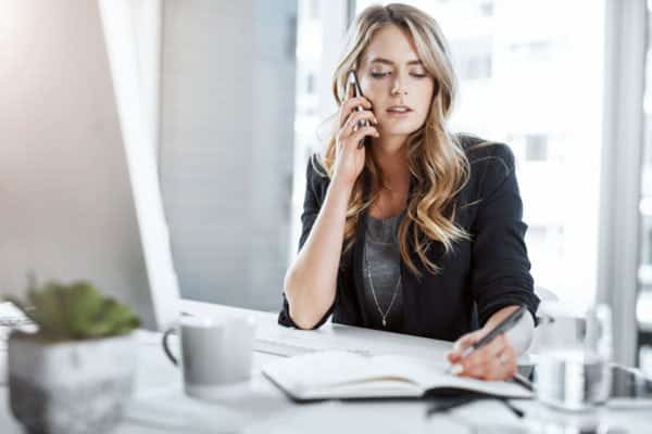 Business woman on the phone taking notes (comparing providers)