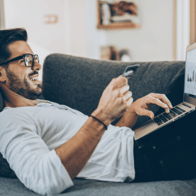 Customer reclines on a couch with laptop and credit card