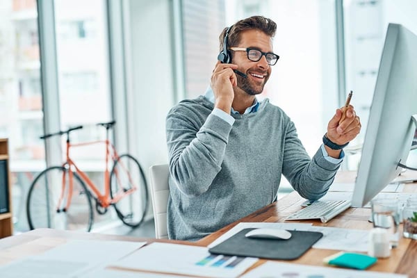 Man at his computer with headset having a delightful conversation